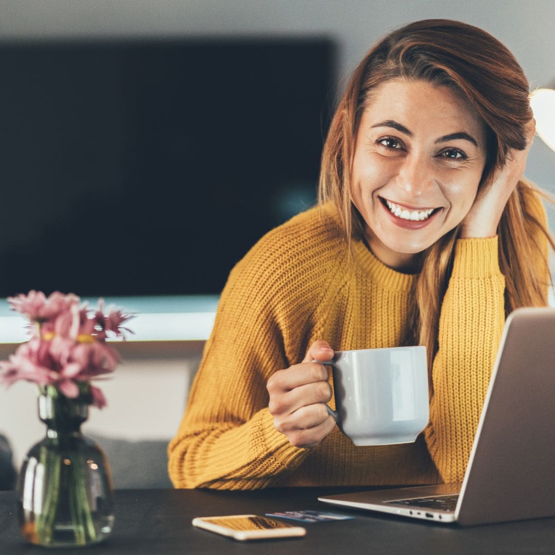 PTS Running your business from home. Smiling woman working with laptop and cup of coffee